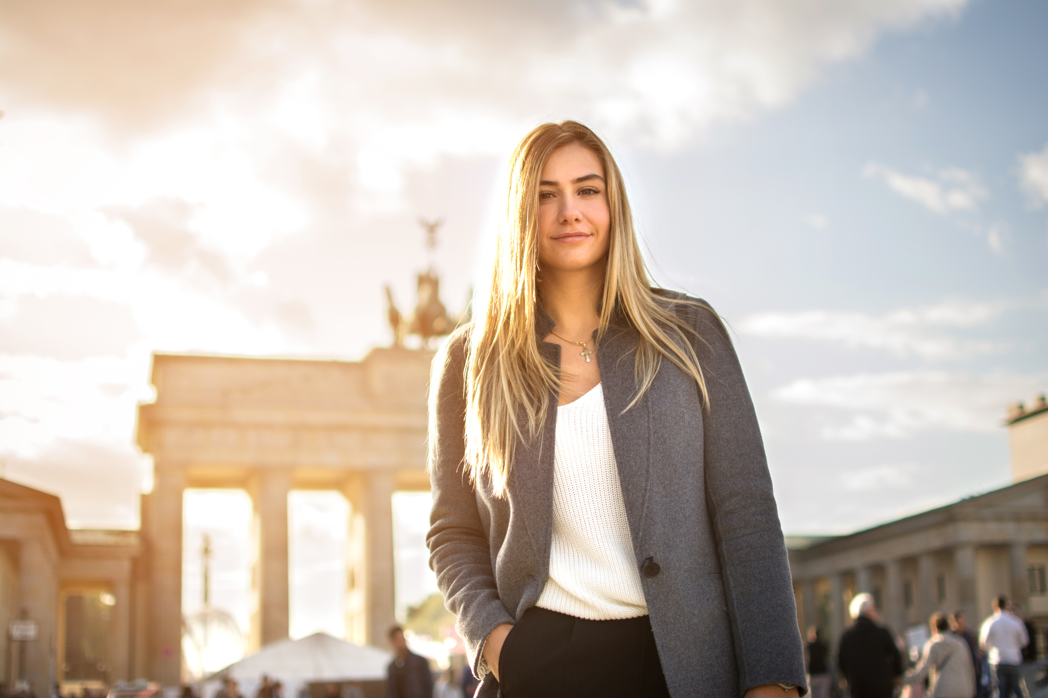 Portrait of smiling fashionable young woman in front of Brandenburger Tor in Berlin, Germany.